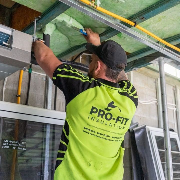 A man wearing a pro-fit insulation shirt is working on a ceiling
