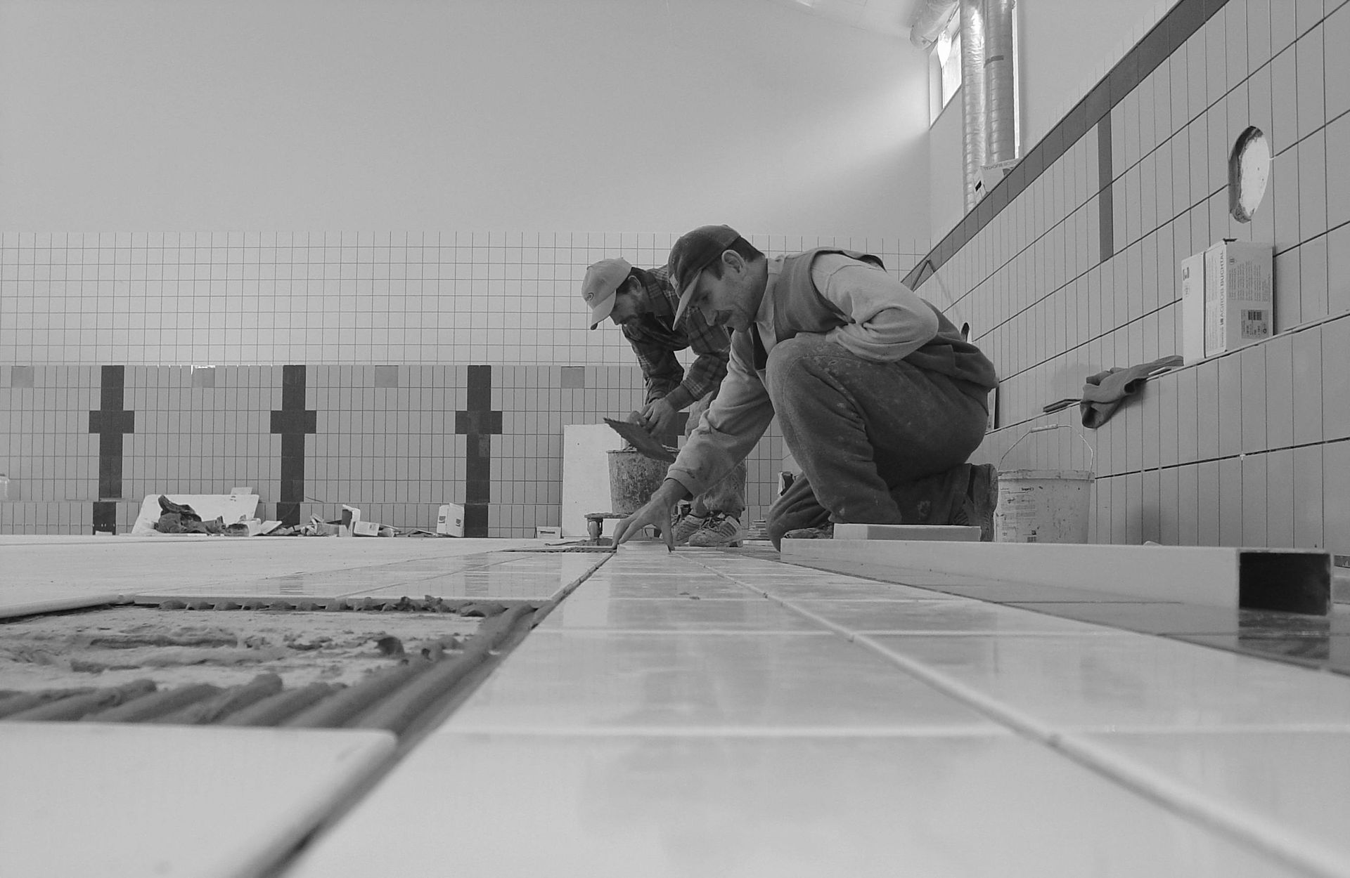 Two workers installing custom tile in a black and white photo