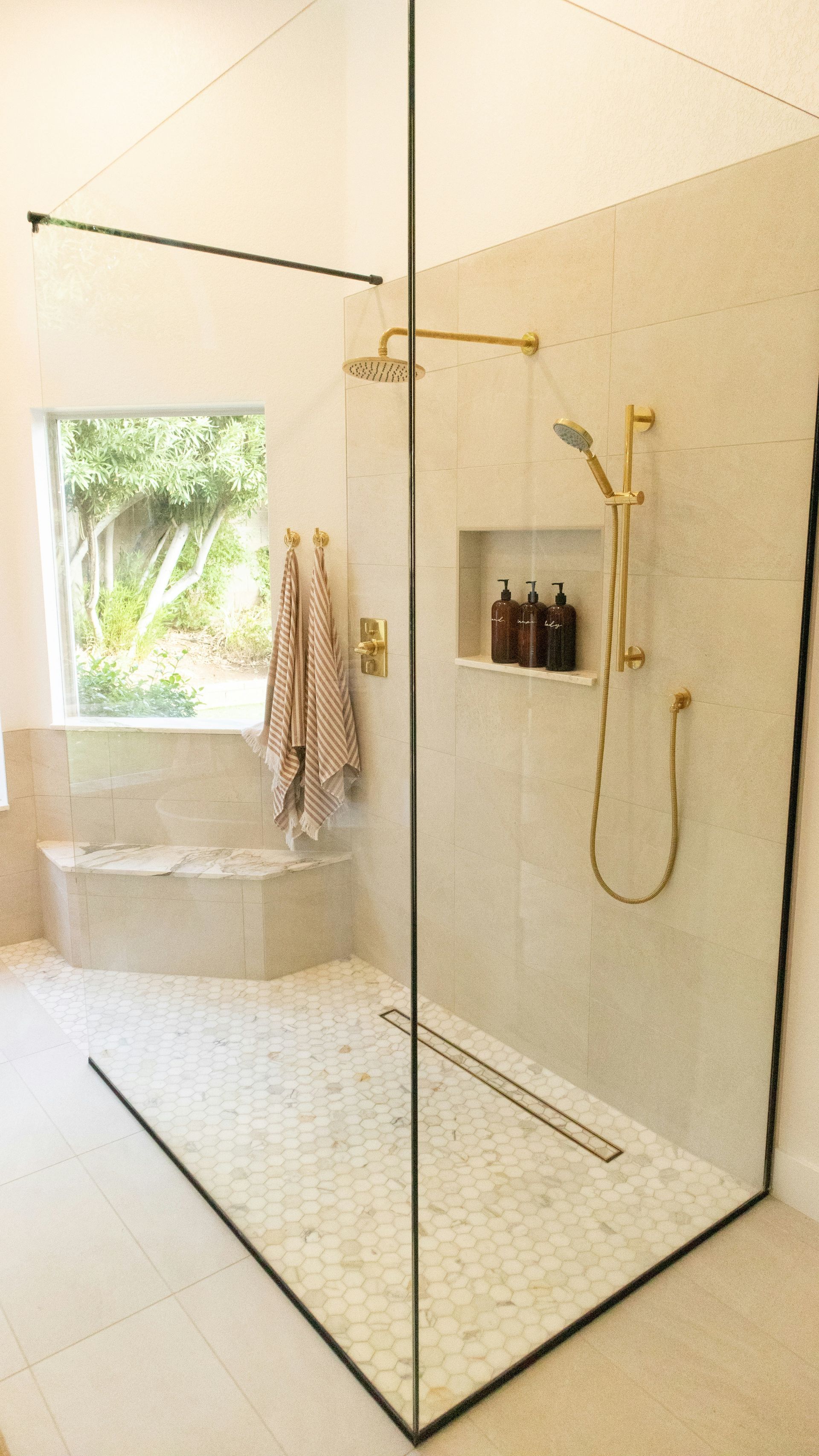 A cream open shower with glass walls