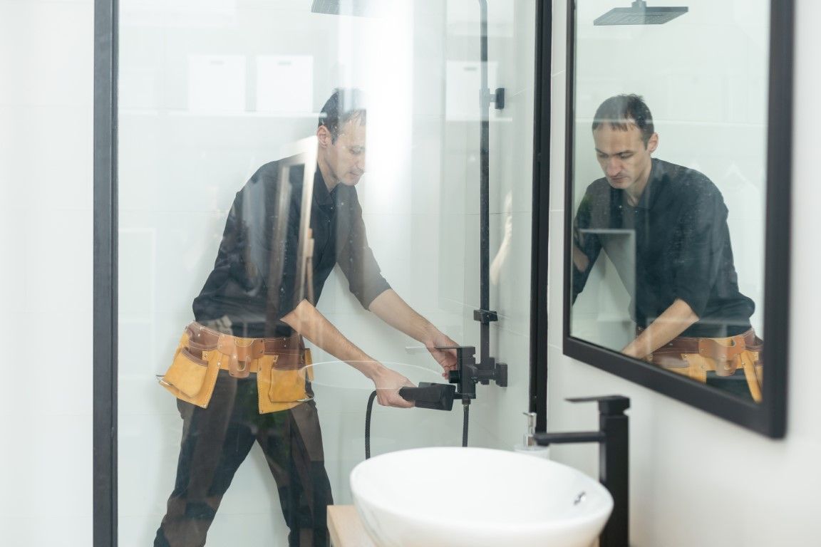 A male worker installs custom shower fixtures.