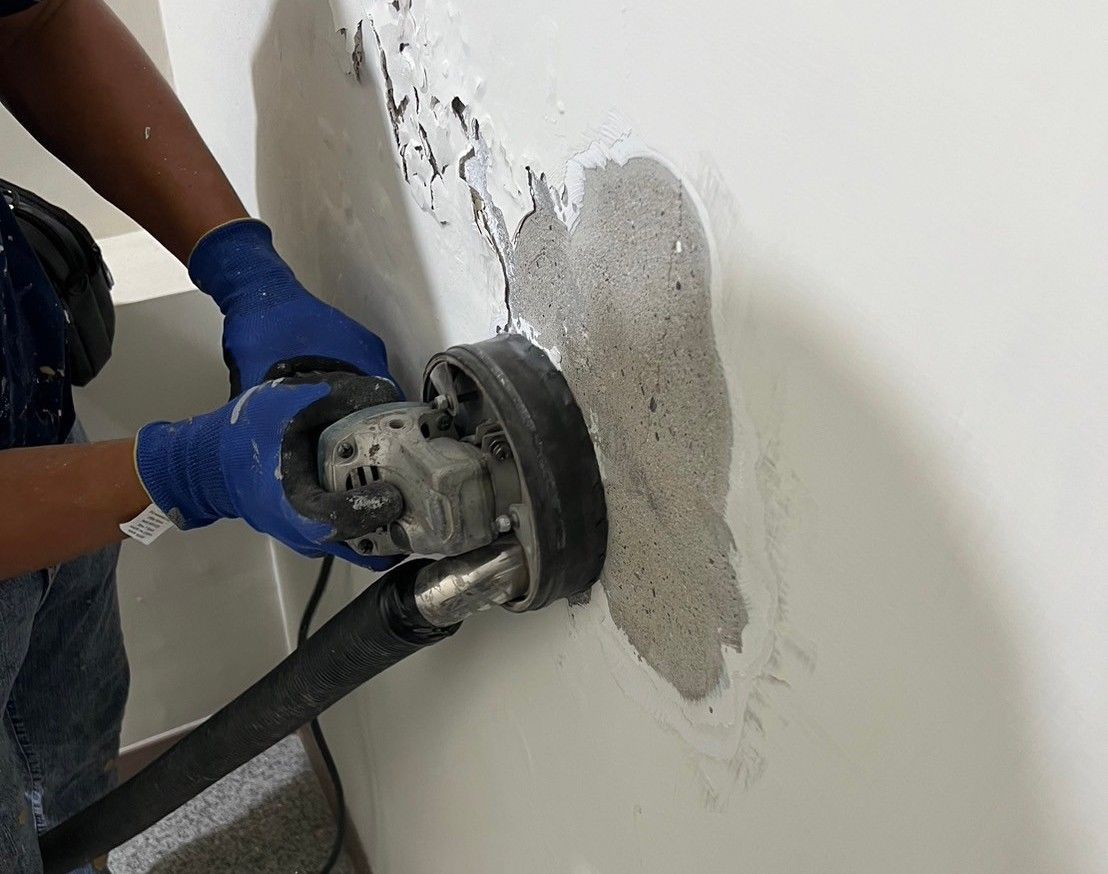 A person is using a grinder on a wall.