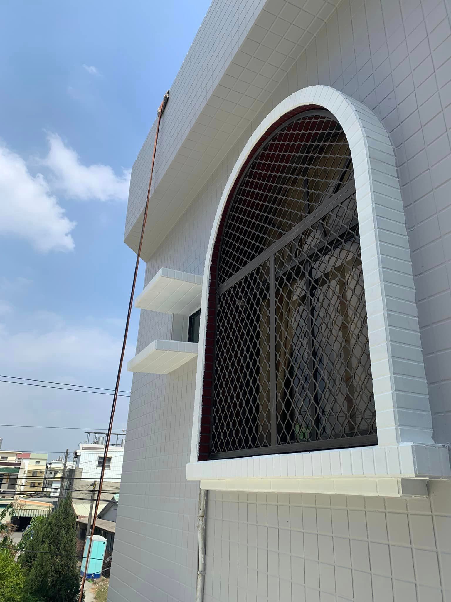 A white brick building with a large arched window