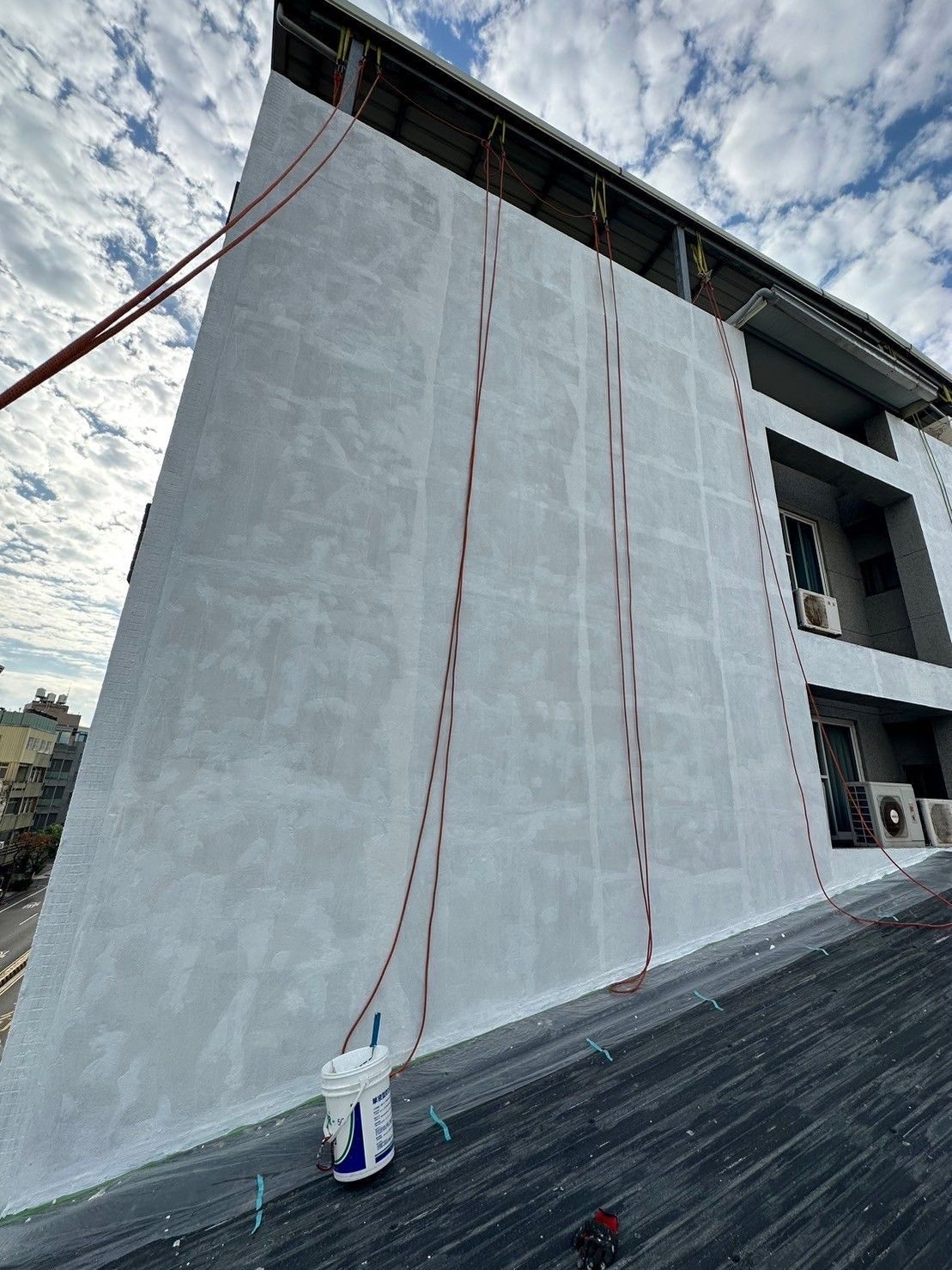A large white building with a bucket on the ground in front of it.