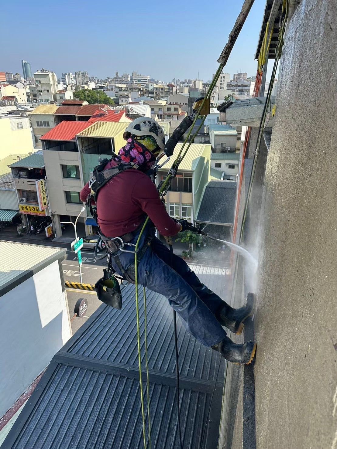 A man is cleaning a building with a high pressure washer.