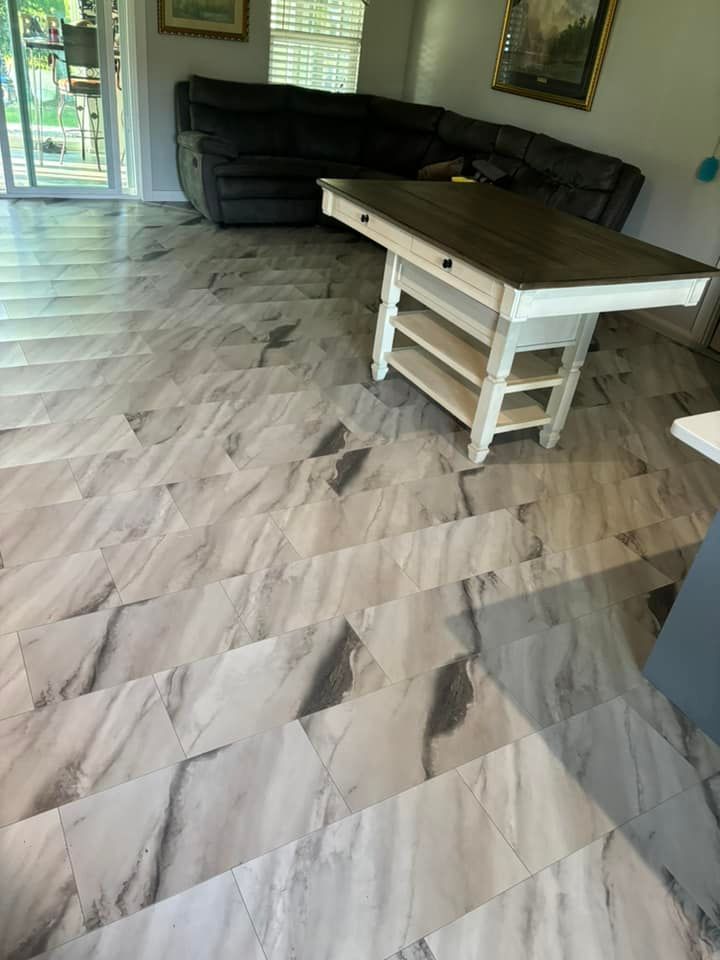 A kitchen with light gray marble-look flooring. A white island with a wood countertop sits in the middle.
