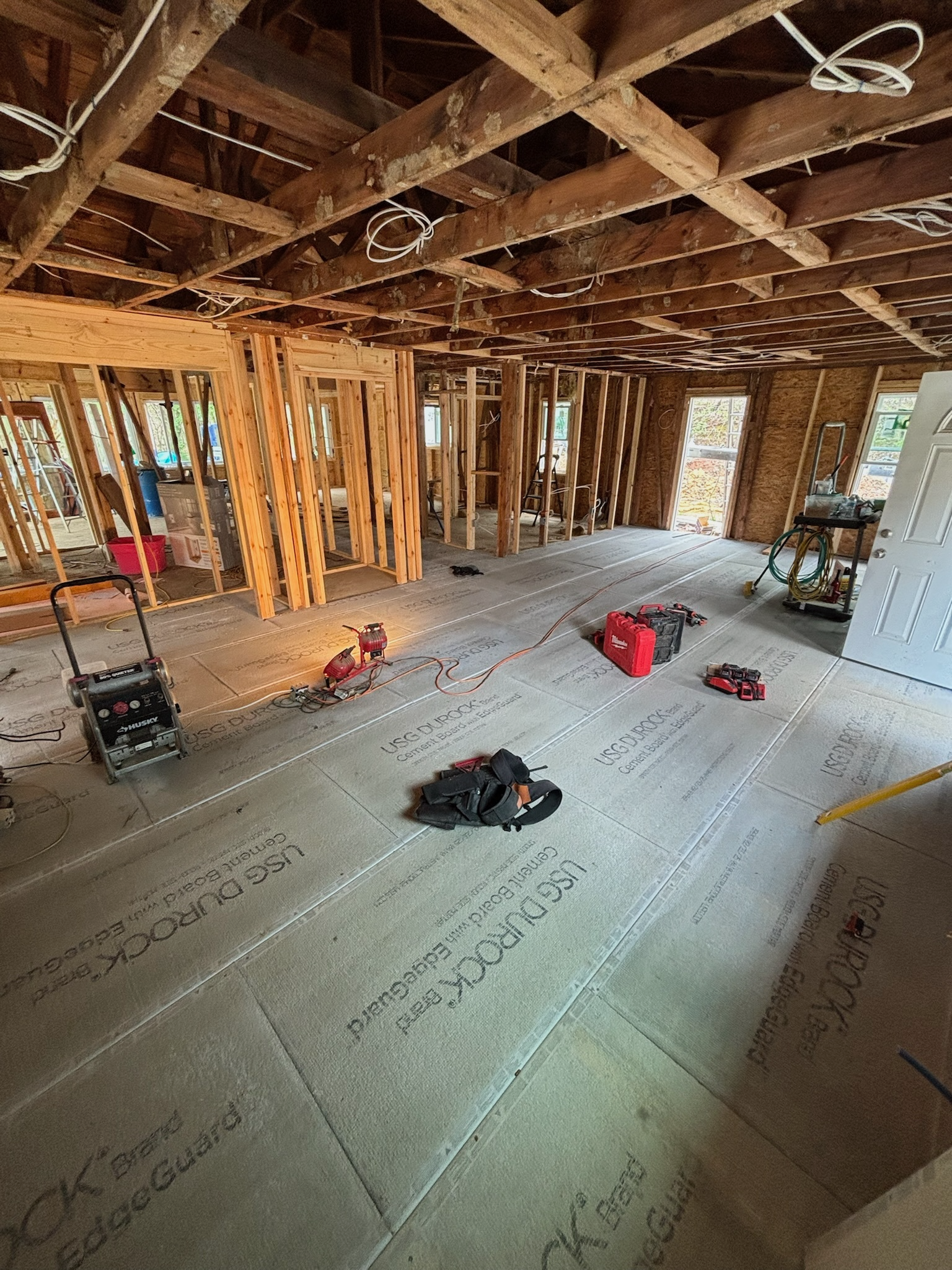 Interior of a building under construction, showing exposed wooden framing and tools on the floor.