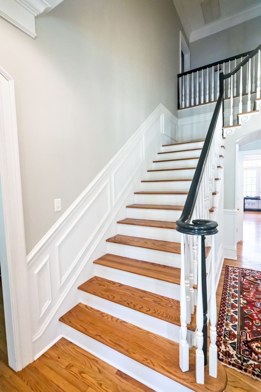 Wooden staircase with white trim and black handrail in a home interior.