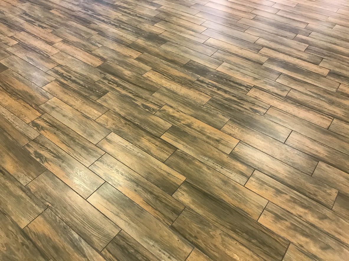 Wood-look tile flooring in shades of brown and gray, with a linear pattern.