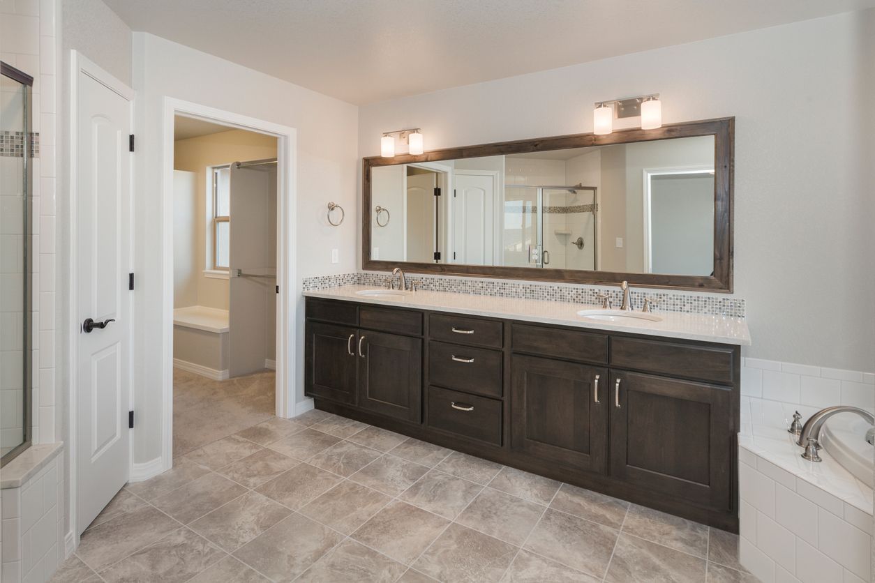 Bathroom with dark wood vanity, large mirror, and neutral-toned tiled floor and walls.