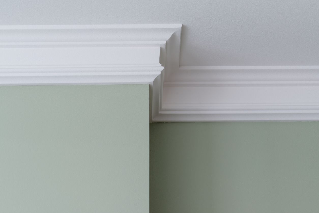 White crown molding at a corner where light green walls meet the ceiling.