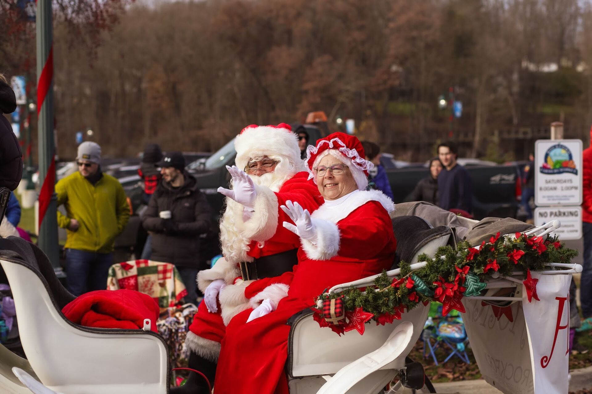 Santa and Mrs. Claus waving from a sleigh in a Christmas parade.