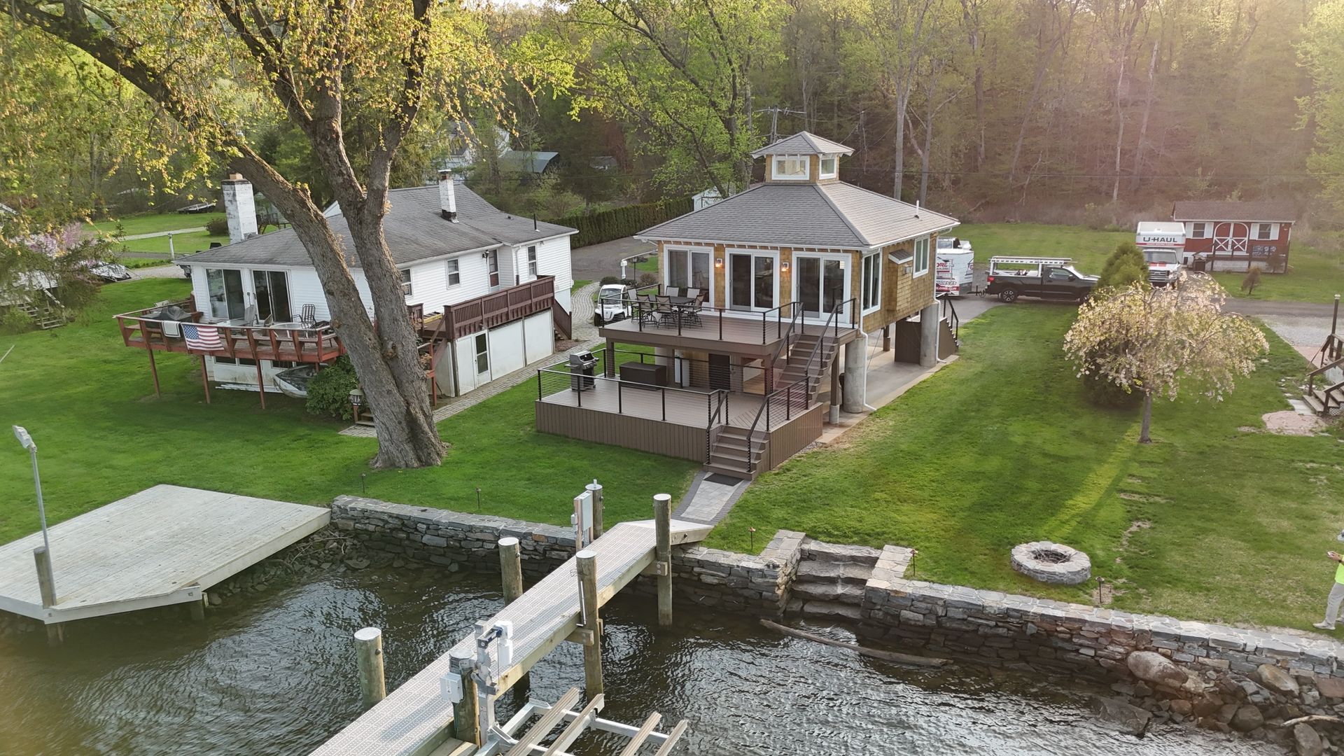 Houses on a lakefront with a dock. Trees and greenery surround the structures.