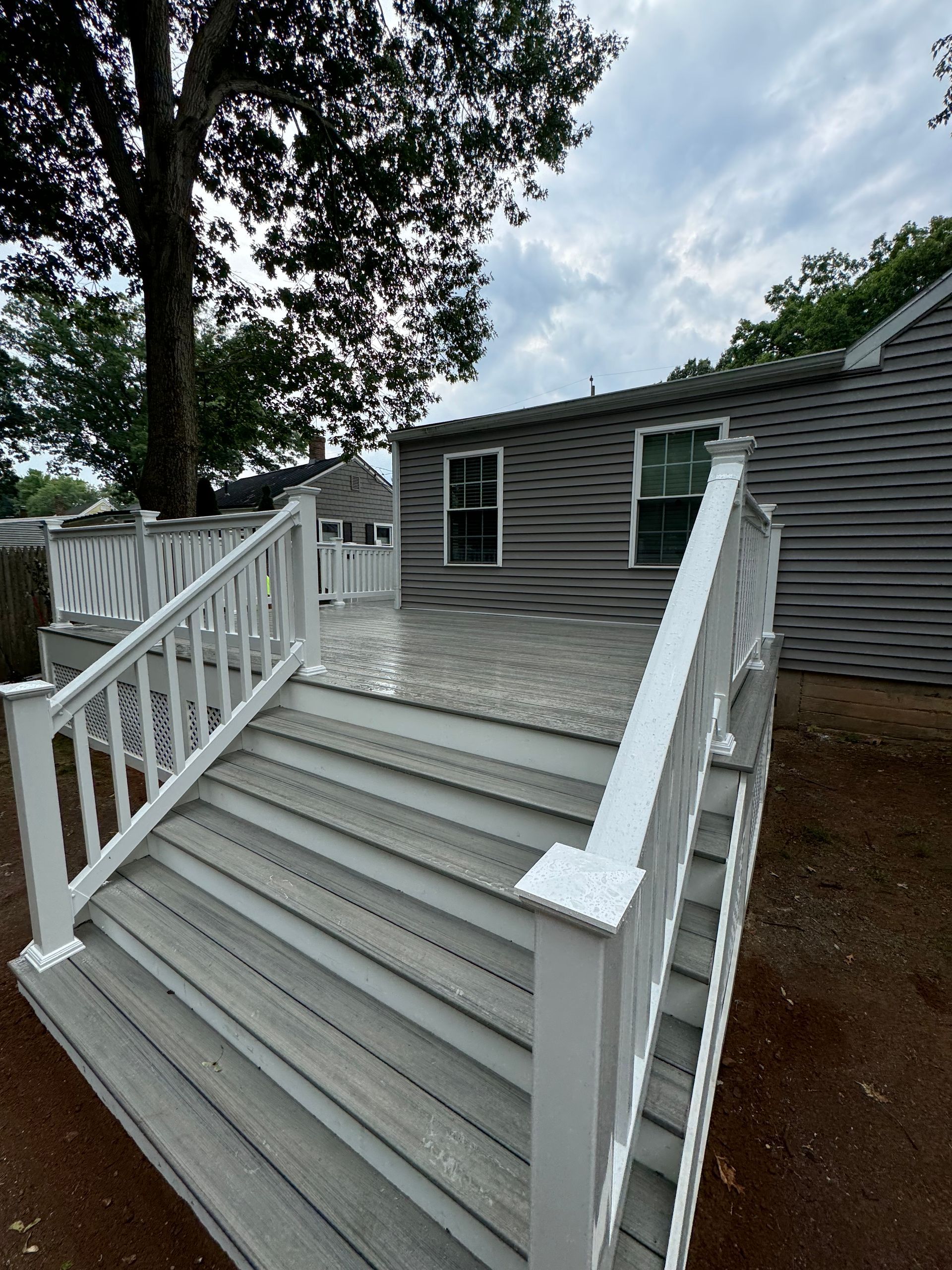 Gray composite deck with white railings, leading to a house with gray siding.