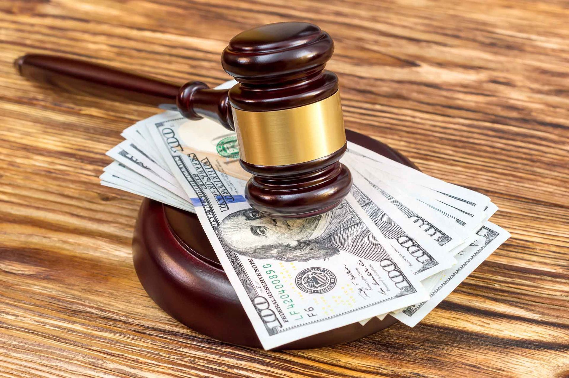 A judge 's gavel is sitting on top of a pile of money on a wooden table.