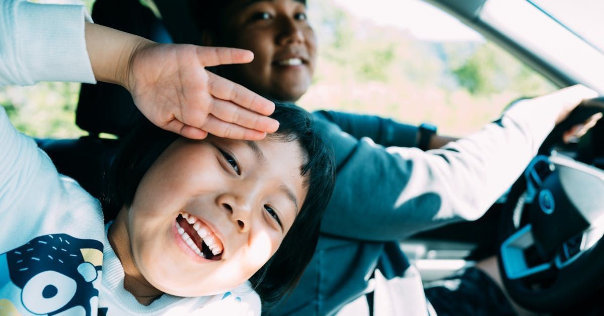 A man is driving a car with a child laying on the back seat.