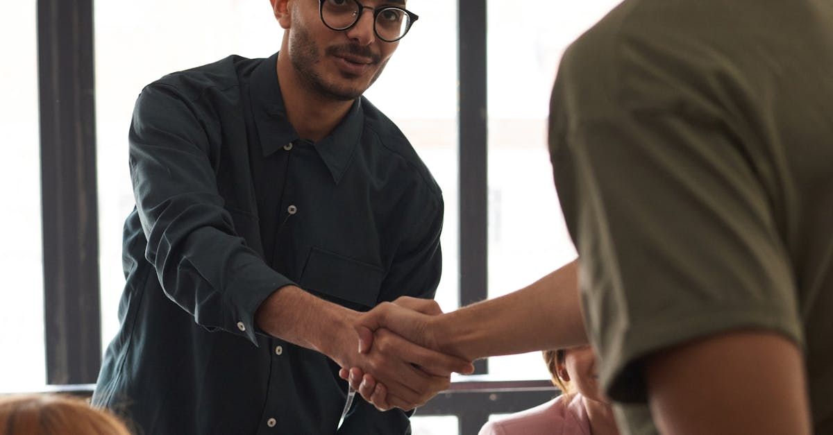 A man is shaking hands with another man in front of a group of people.