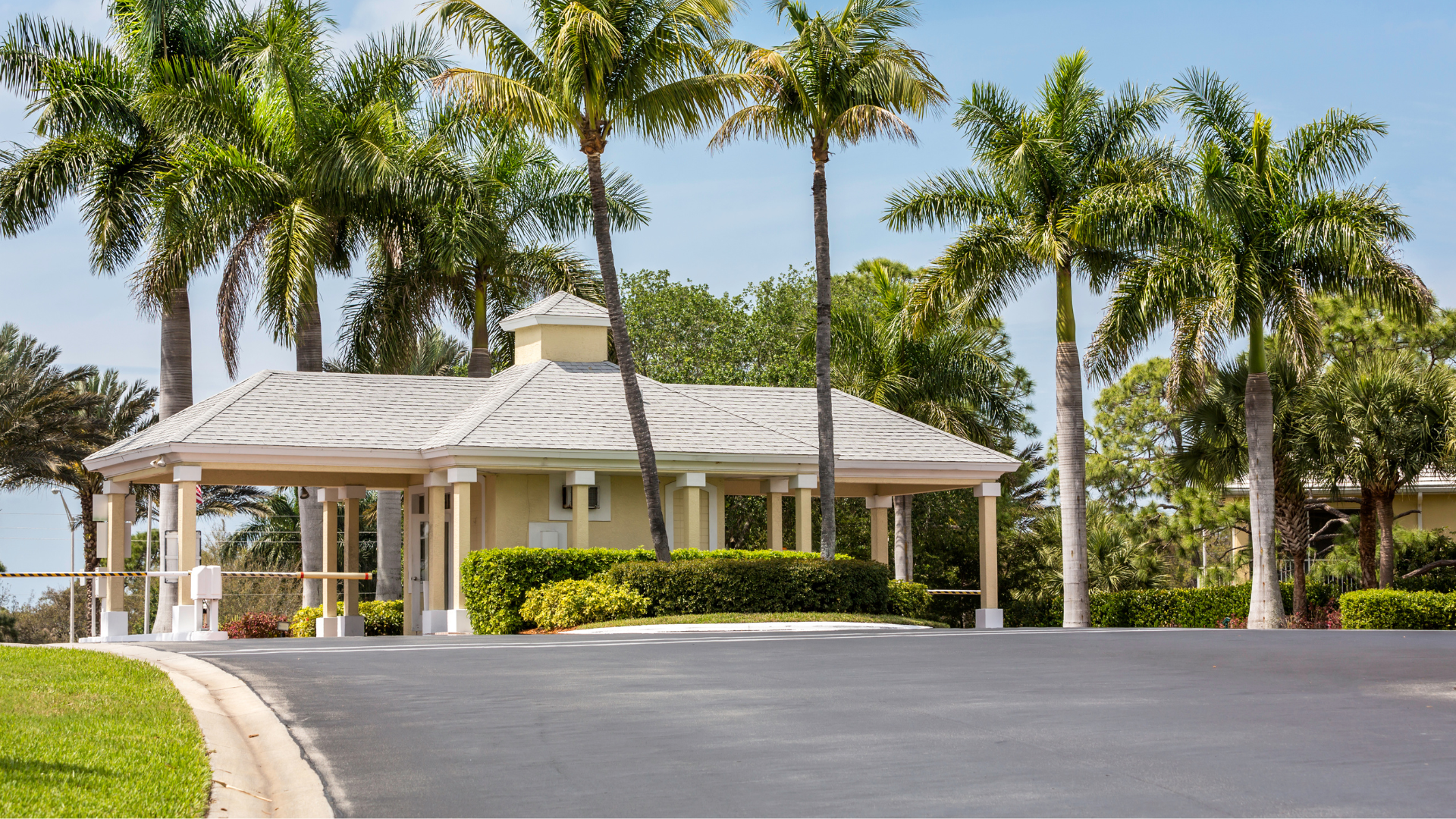 A house with palm trees in front of it and a driveway leading to it.