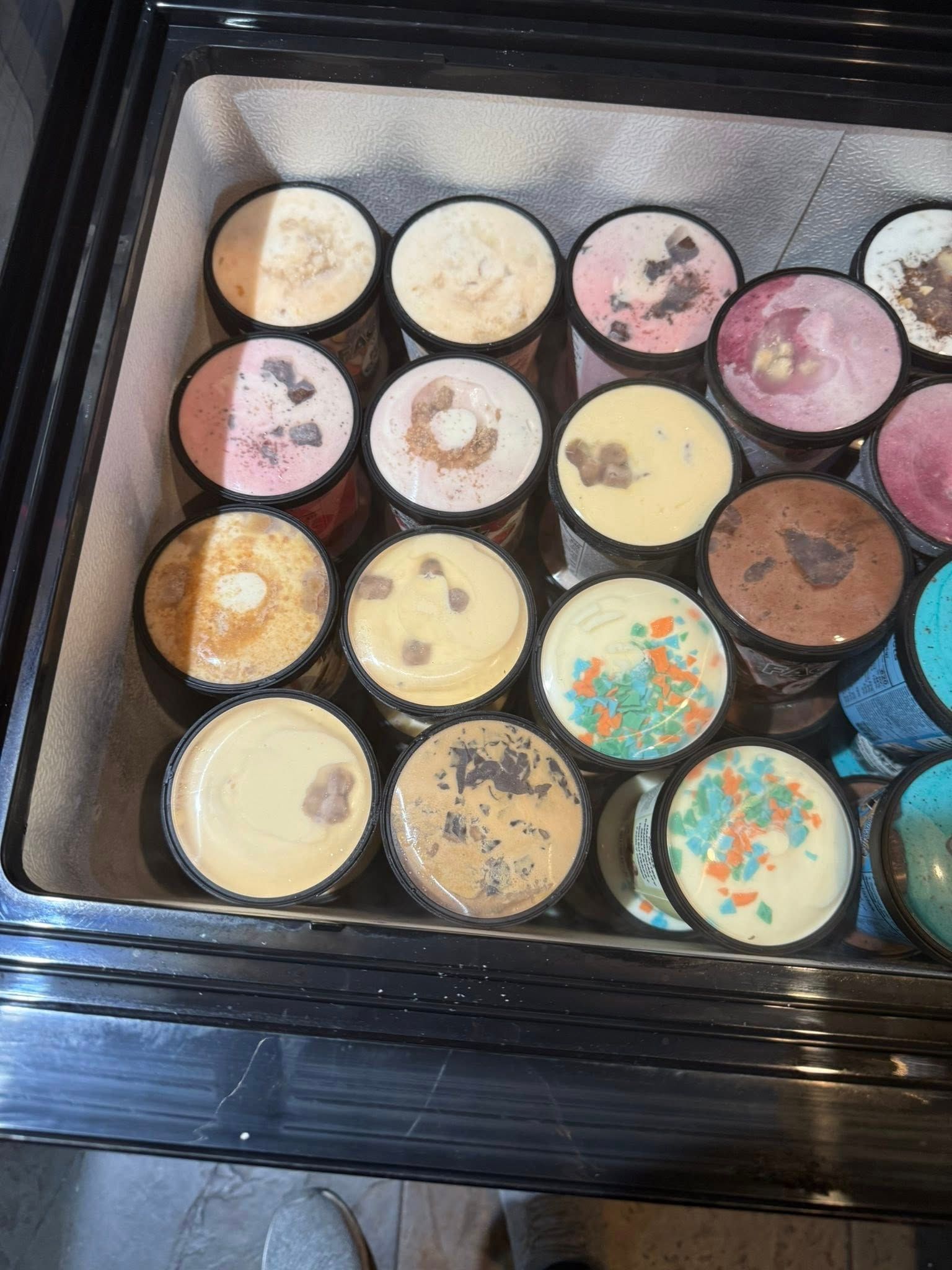 Display case of ice cream tubs in various flavors.