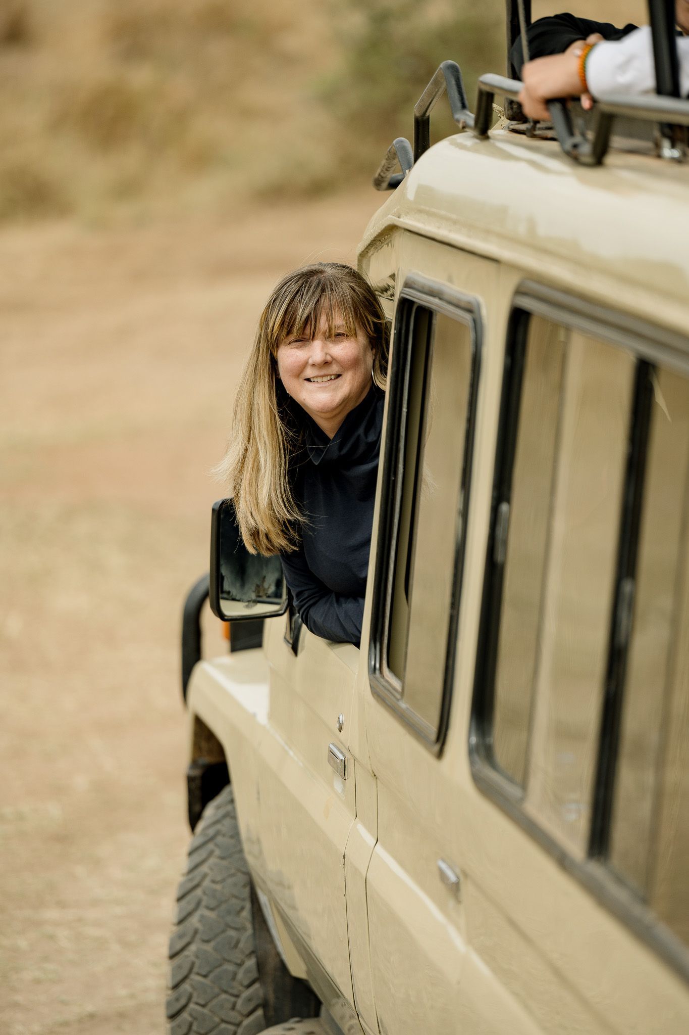 A woman is looking out of the window of a jeep.