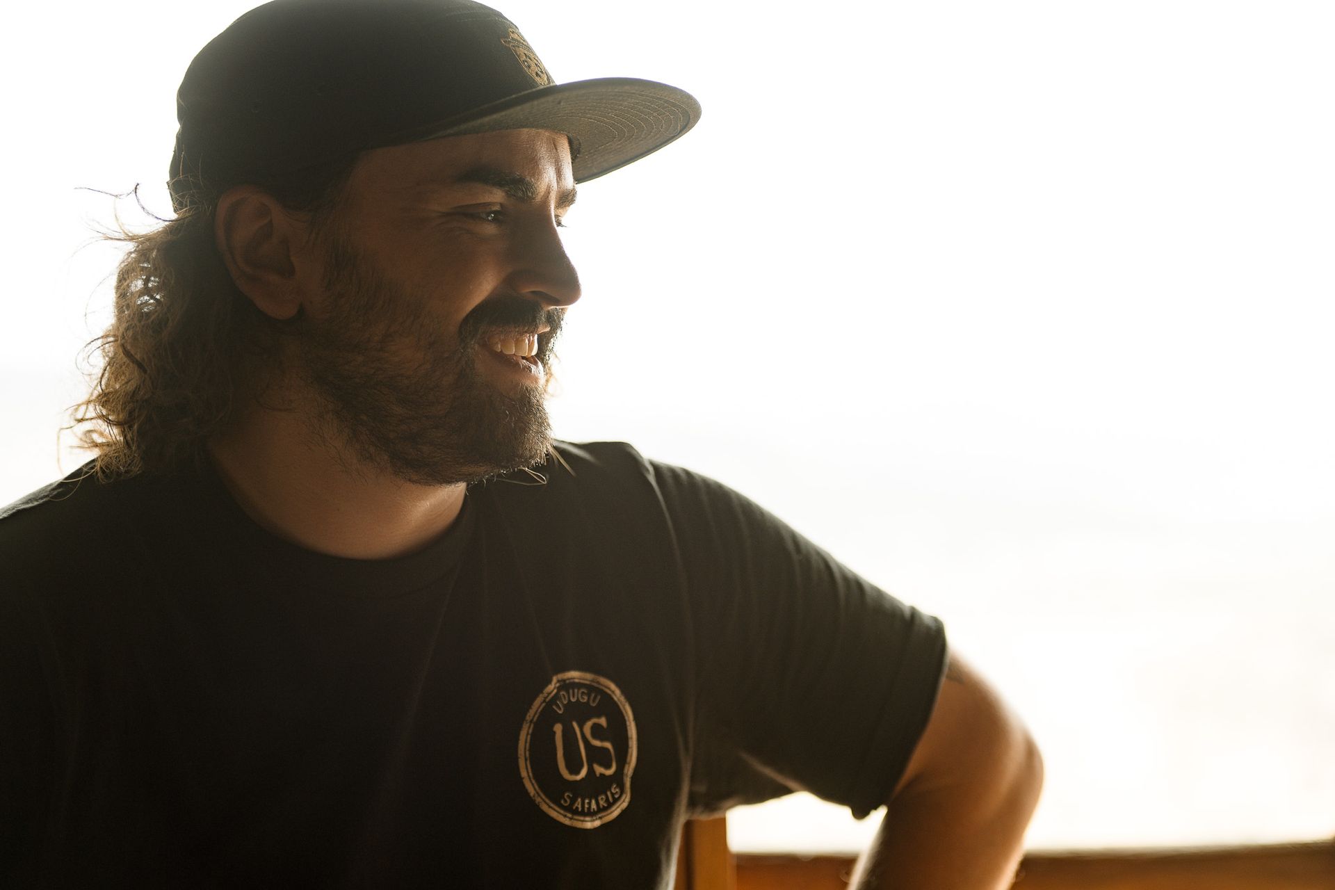 A man with a beard is wearing a hat and a black shirt.