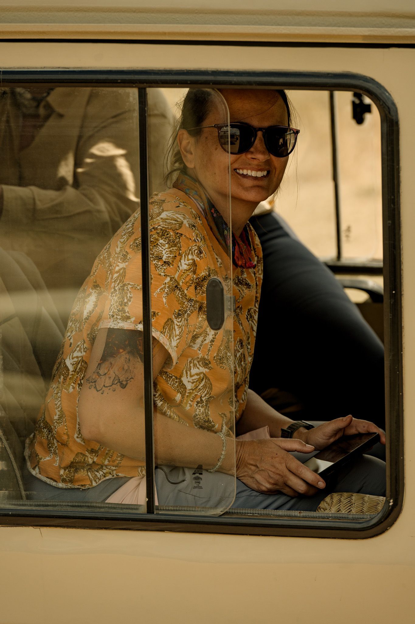 A man wearing sunglasses is sitting in the back seat of a car.