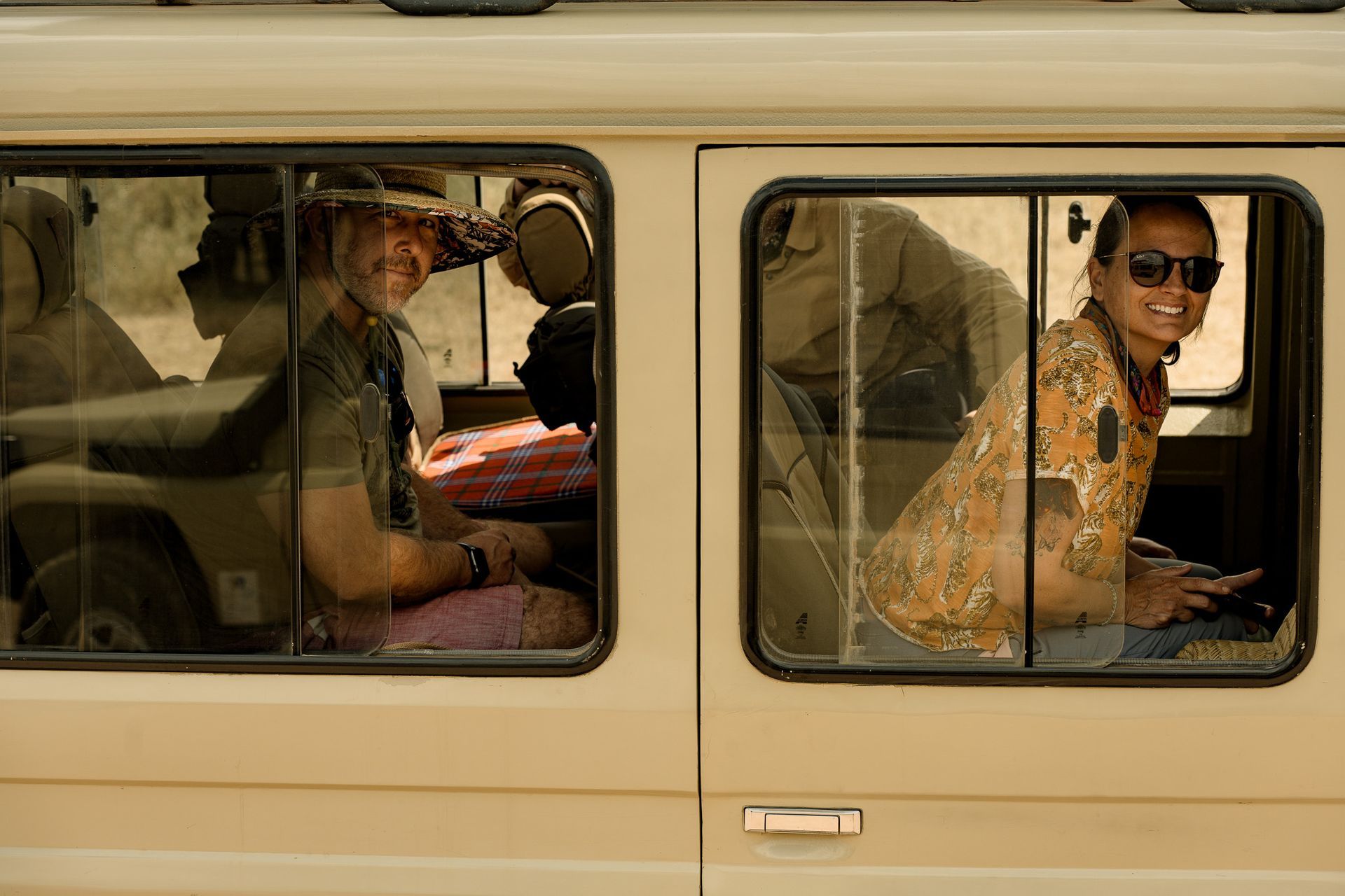 A man and a woman are sitting in a van looking out the windows.