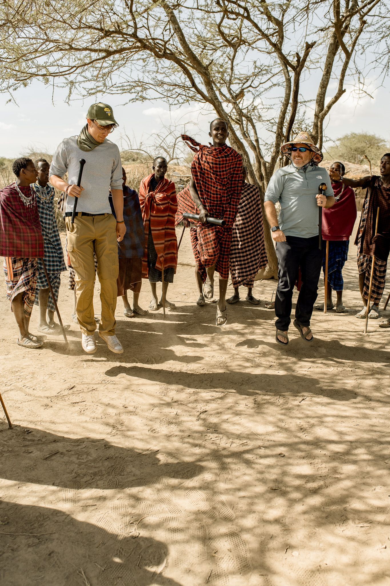 A group of people are standing in a dirt field.