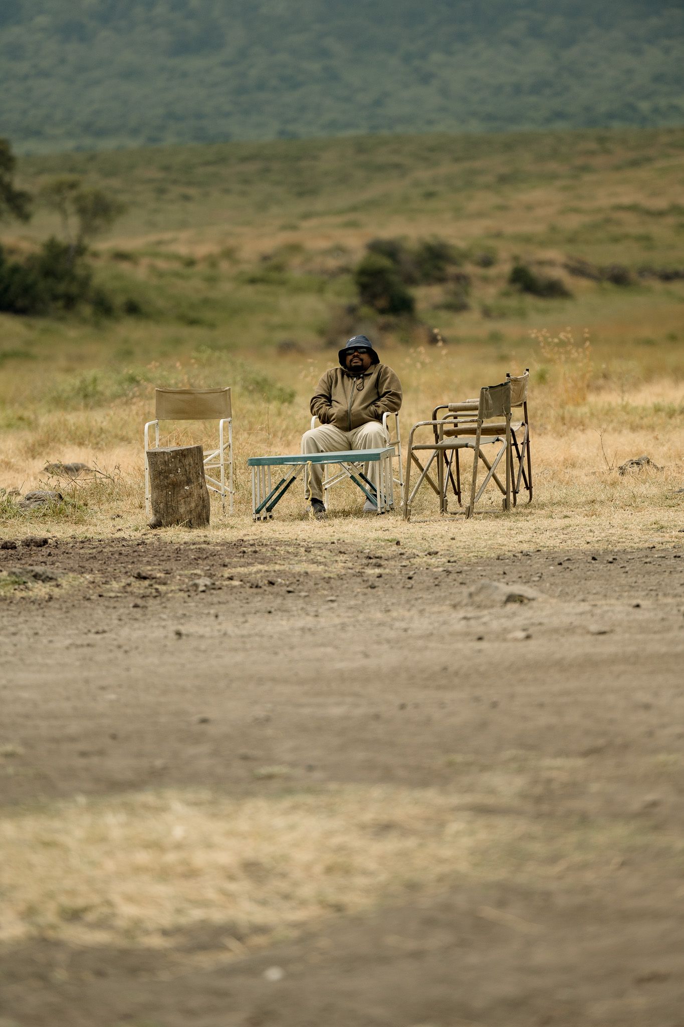 A man is sitting on a bench in the middle of a field.