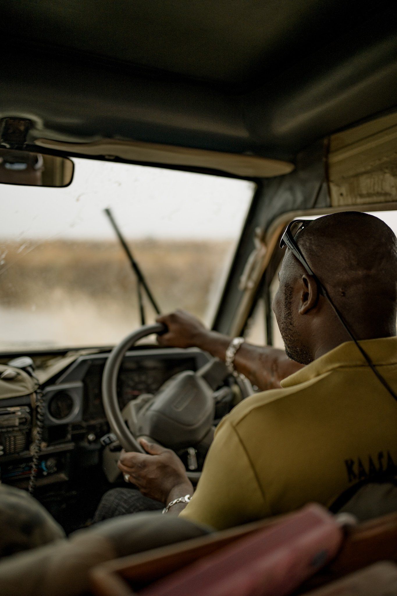 A man in a yellow shirt is driving a car.