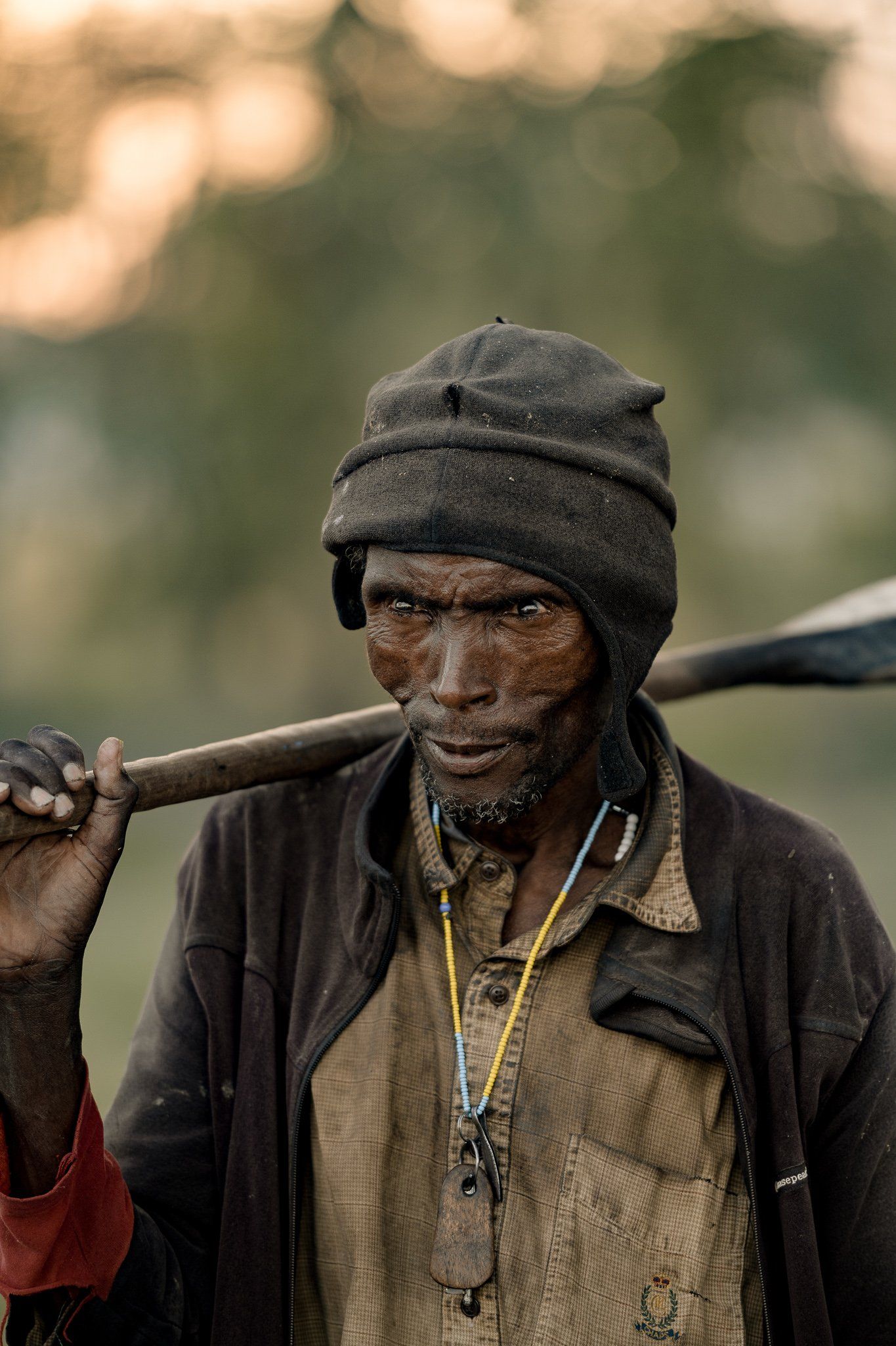 A man is carrying a large stick on his shoulder.