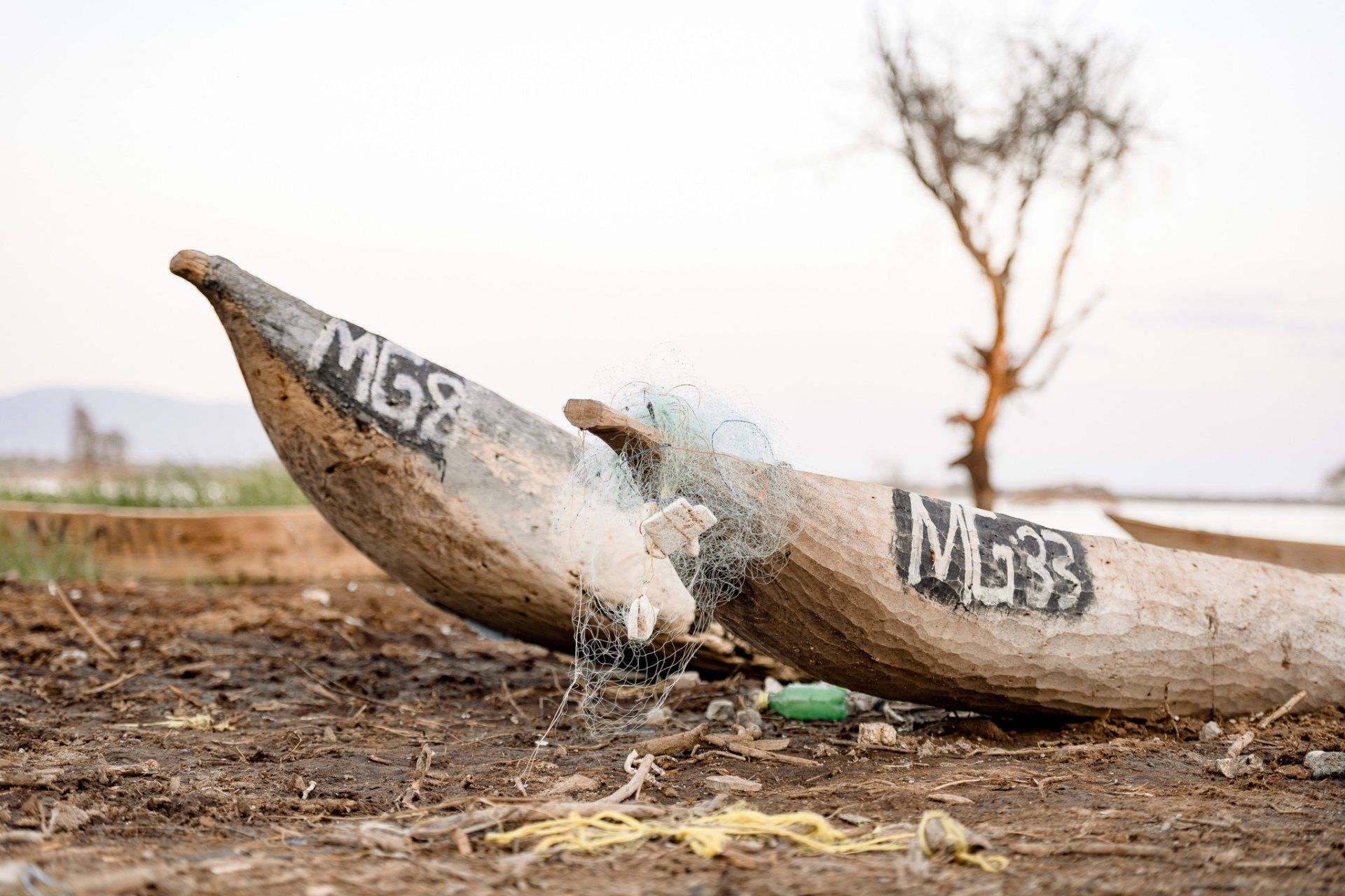 Two wooden boats are sitting on top of a dirt field.