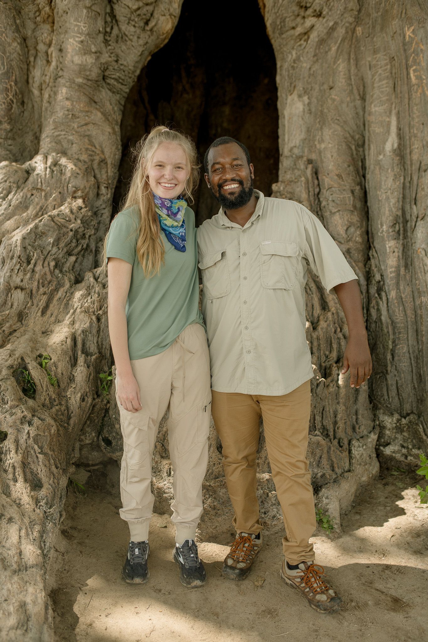 A man and a woman are posing for a picture in front of a tree.
