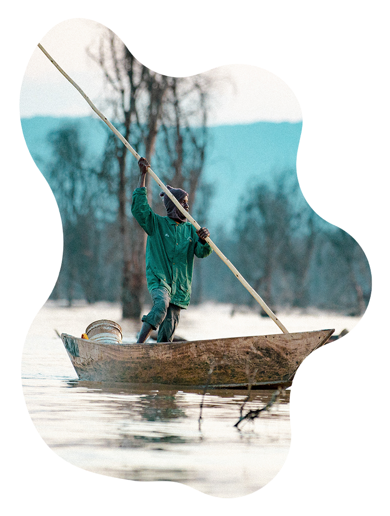 A man in a green jacket is rowing a boat in the water.