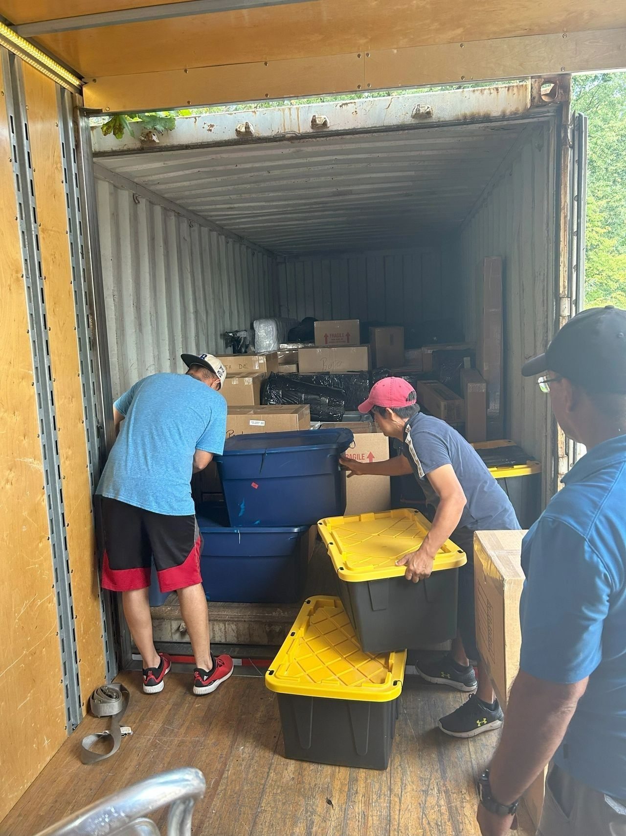 Two men are loading boxes into a shipping container.