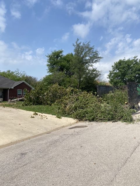 A man is pushing a tree chipper down a gravel road.