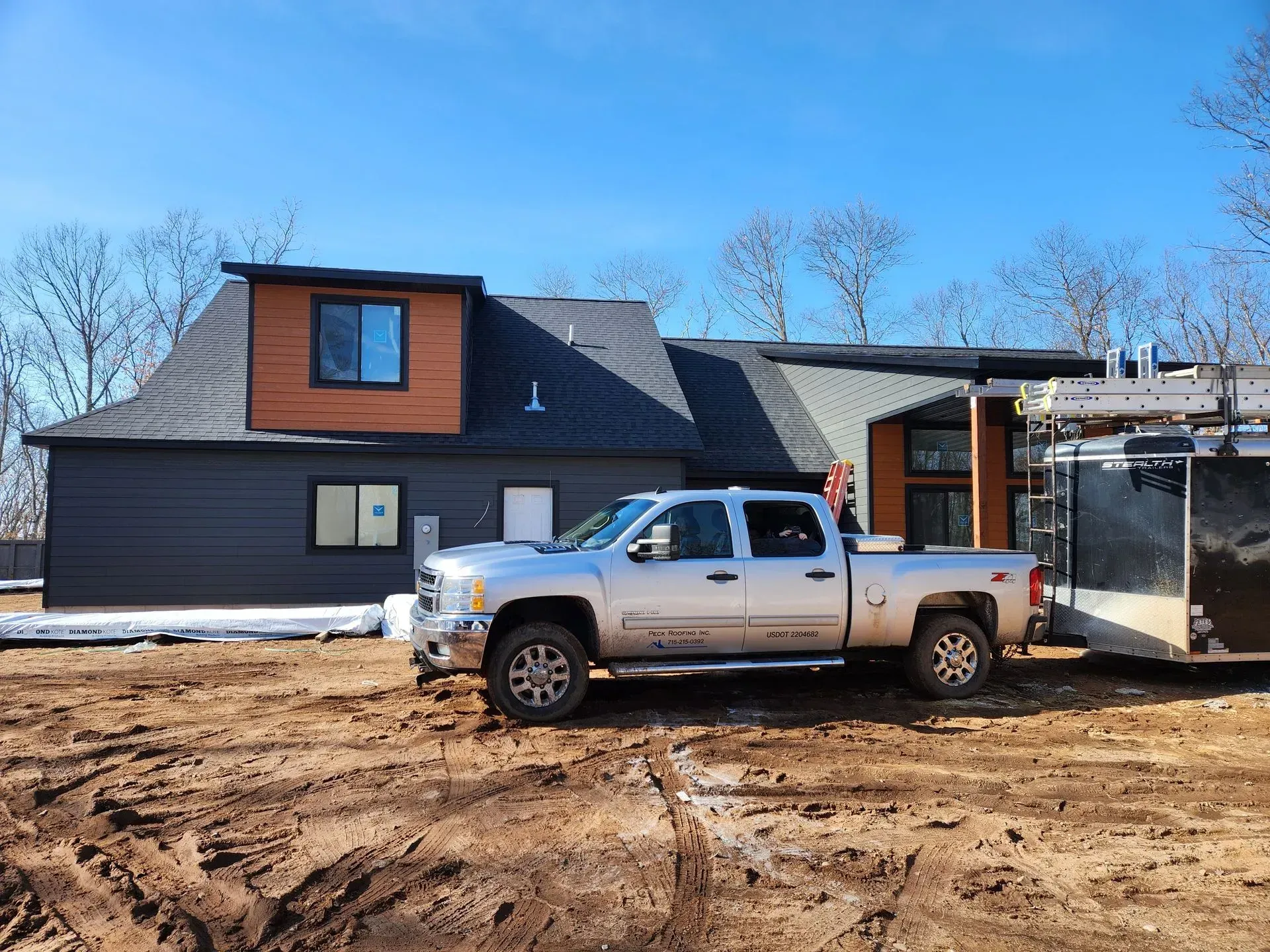 A silver truck is parked in front of a house under construction.