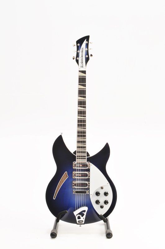 A blue and white electric guitar is sitting on a stand on a white background.