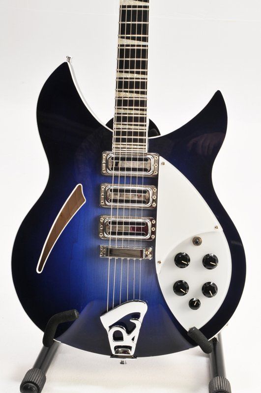A blue and white rickenbacker guitar is sitting on a stand
