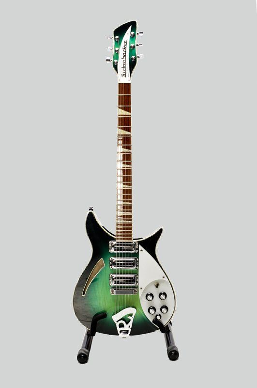 A green and black electric guitar is sitting on a stand.
