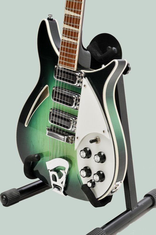 A green and black electric guitar is sitting on a stand