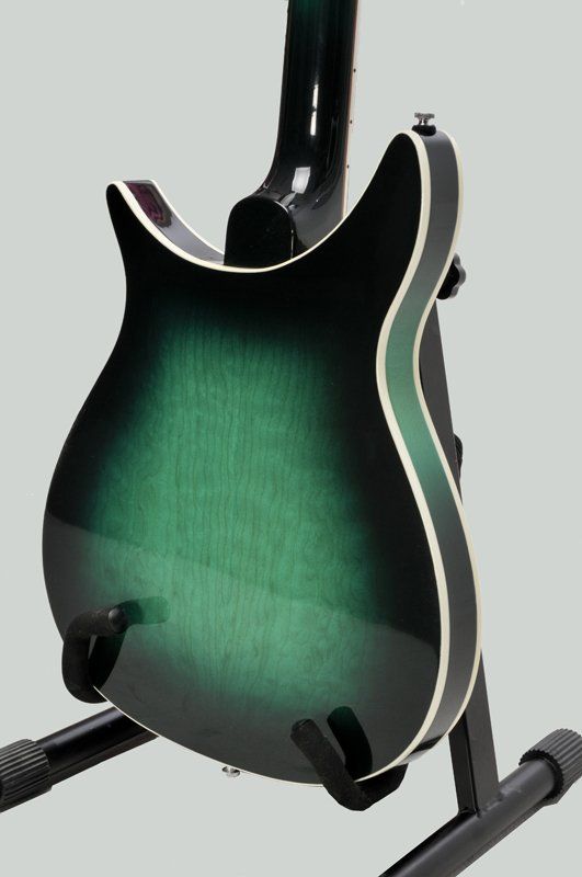 A green and black electric guitar is sitting on a stand.