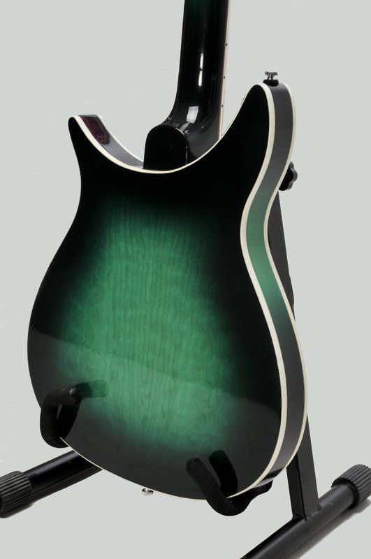 A green and black guitar is sitting on a stand