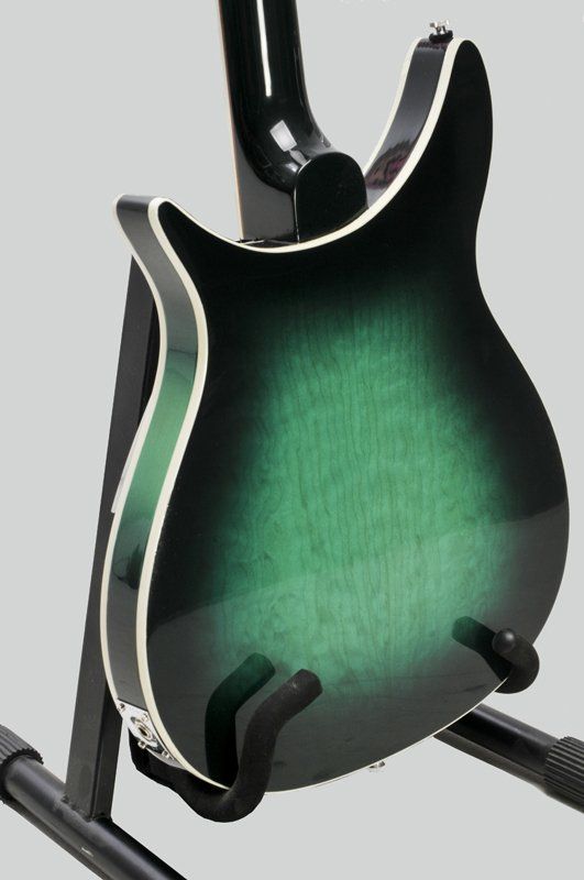 A green and black electric guitar is sitting on a stand.