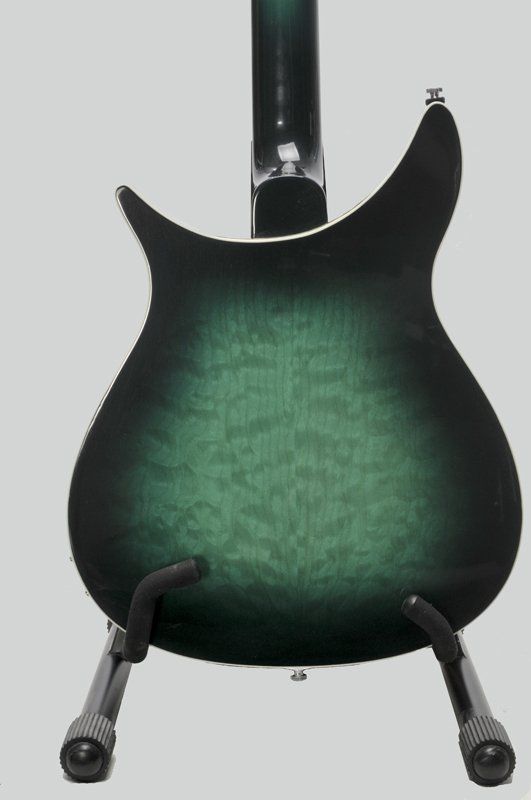 A green and black guitar is sitting on a stand