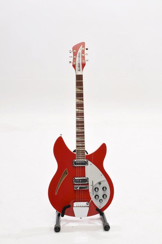 A red electric guitar is sitting on a stand on a white background.