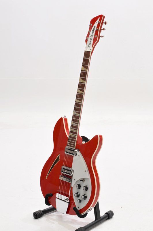 A red electric guitar is sitting on a stand on a white background.