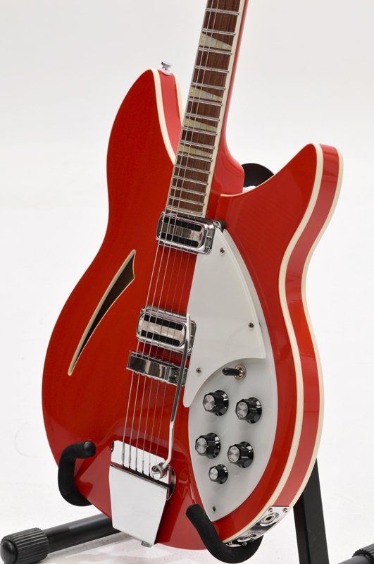 A red and white guitar is sitting on a stand