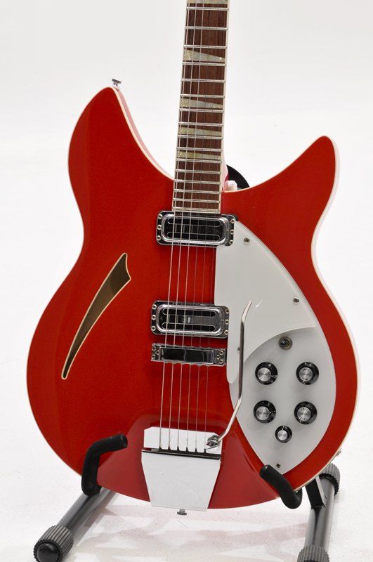 A red and white guitar is sitting on a stand