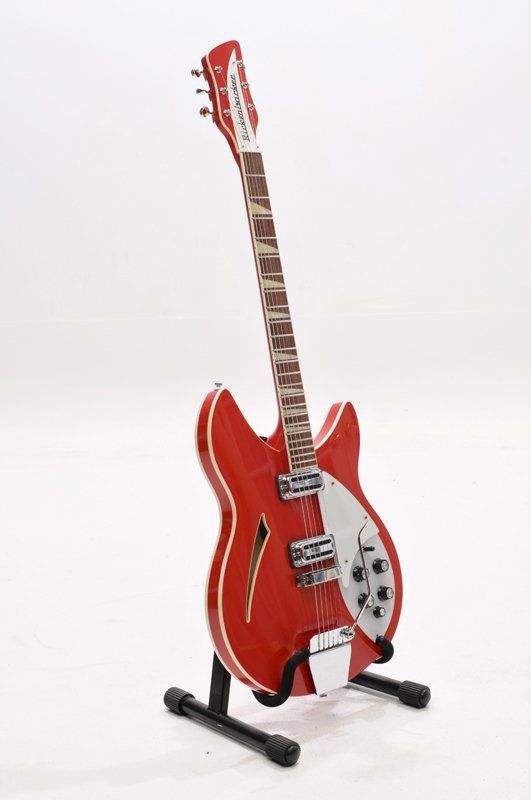 A red electric guitar is sitting on a stand on a white background.