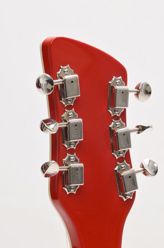 A close up of the headstock of a red guitar